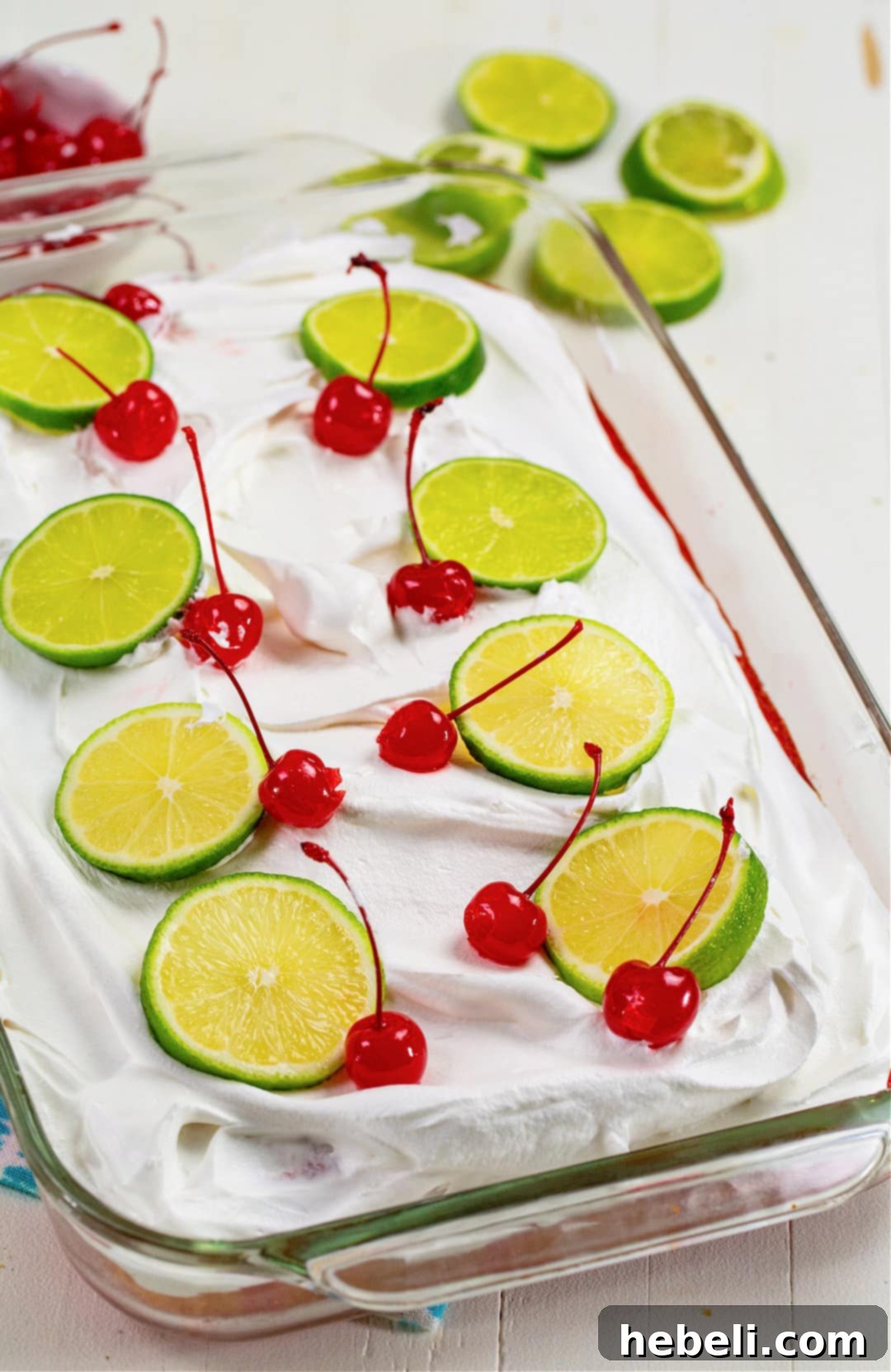 A freshly baked Cherry Limeade Poke Cake in a 9x13-inch baking dish, with holes poked on its surface.