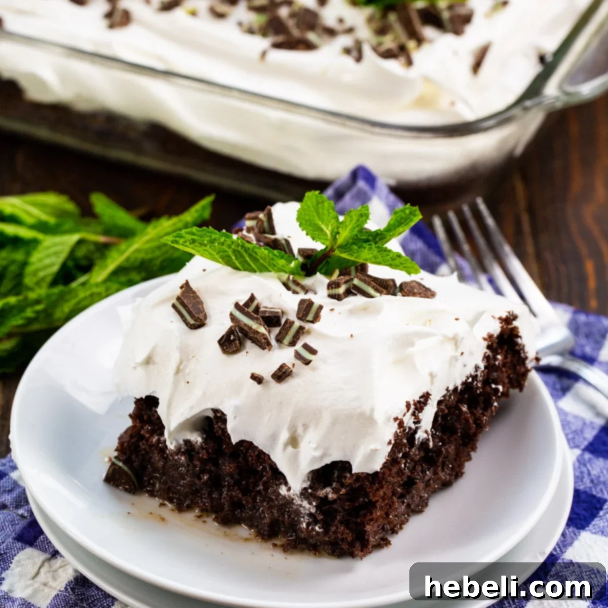 Bourbon Mint Infused Delight 2 A slice of Mint Julep Poke Cake on a small white plate, showcasing its layers and topping.