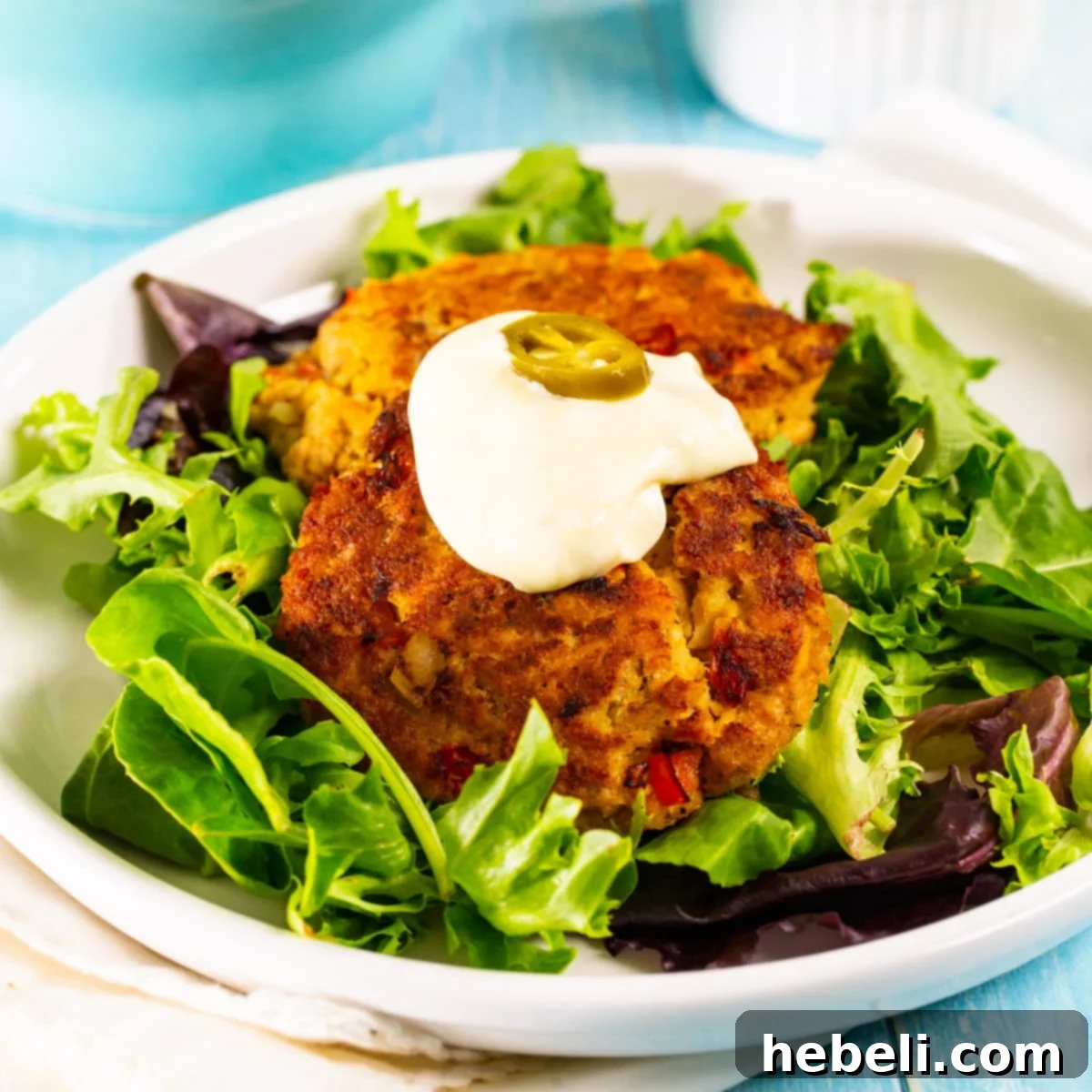 Zesty Bayou Salmon Fritters 2 Golden brown Cajun Salmon Cakes on a bed of fresh mixed greens, drizzled with spicy Jalapeño Mayonnaise.