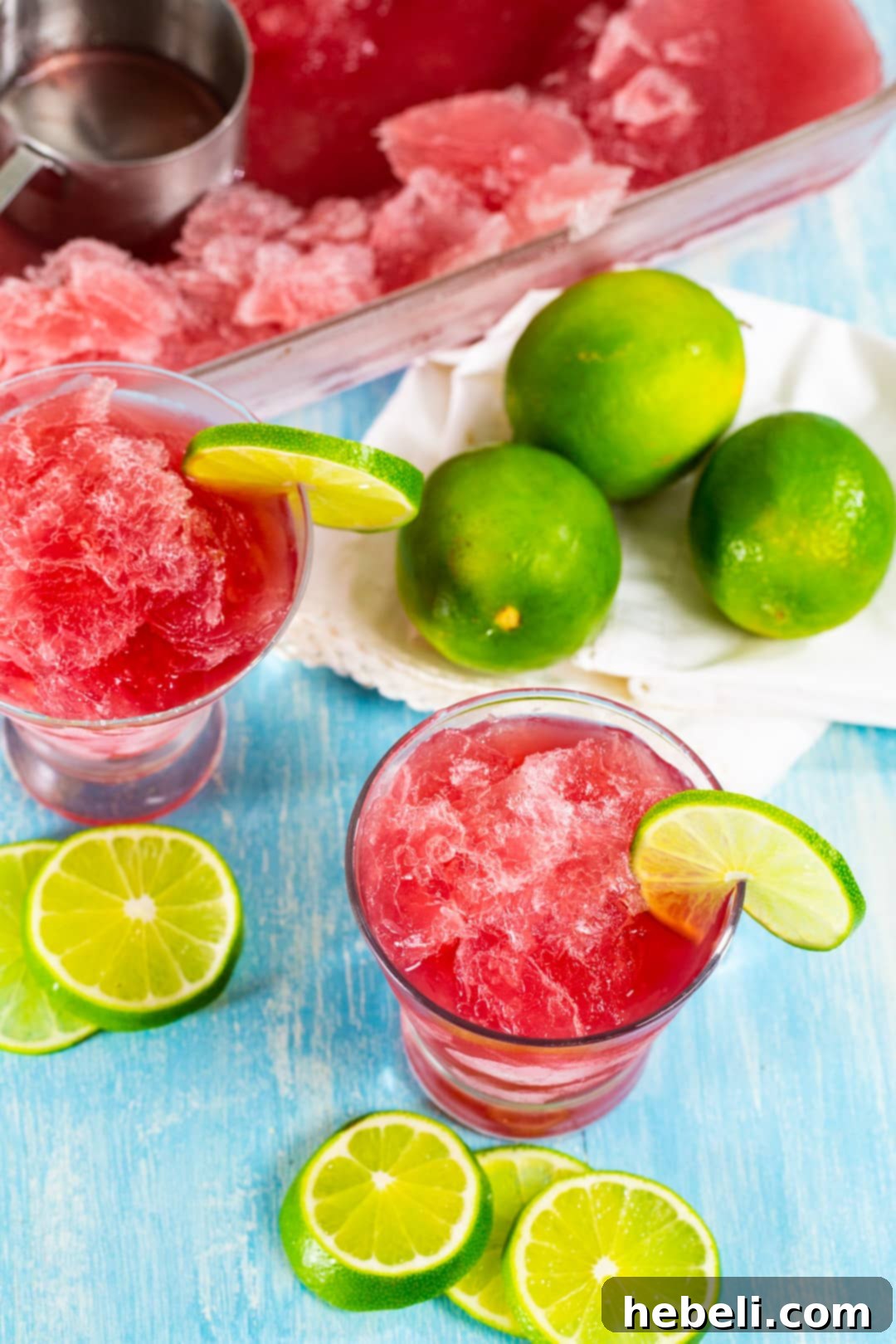 Close-up of Cosmo Slushie in a glass, with fresh limes in the background.