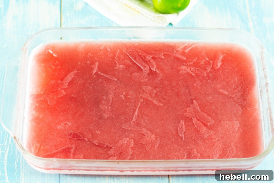 Frozen Cosmo Slush mixture in a 9x13-inch pan, ready to scoop.