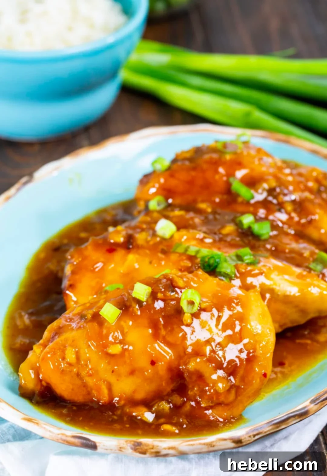 Slow Cooker Orange Chicken on serving plate and bowl full of rice.