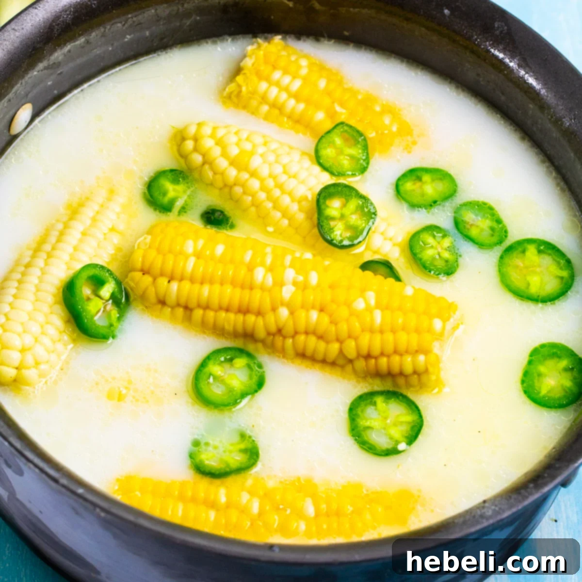 Sweet Heat Honey Butter Corn 2 Jalapeno Honey Butter Corn cooking in a large pot, with vibrant corn cobs and sliced jalapenos.