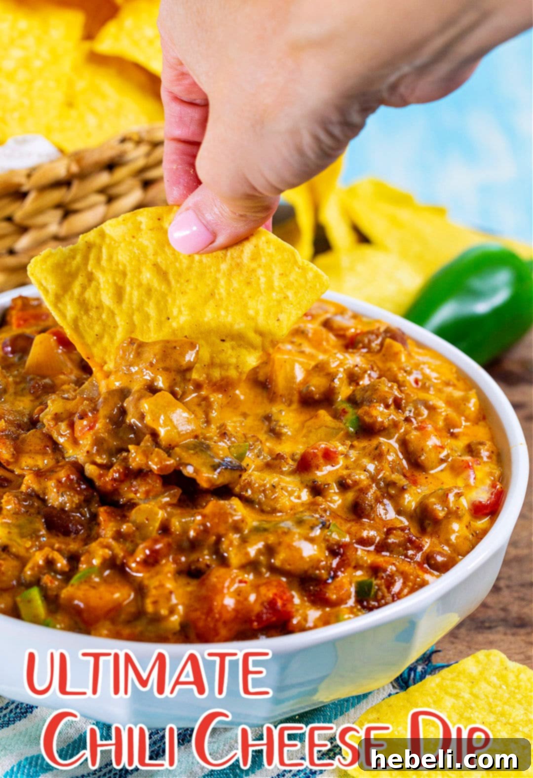 Legendary Chili Cheese Dip 5 Hand dipping chip into cheese dip.