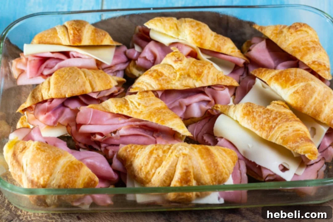 Savory Ham and Cheese Croissant Bake 4 Close-up view of ham and cheese stuffed mini croissants arranged neatly in a baking dish, before the egg mixture is poured over them.