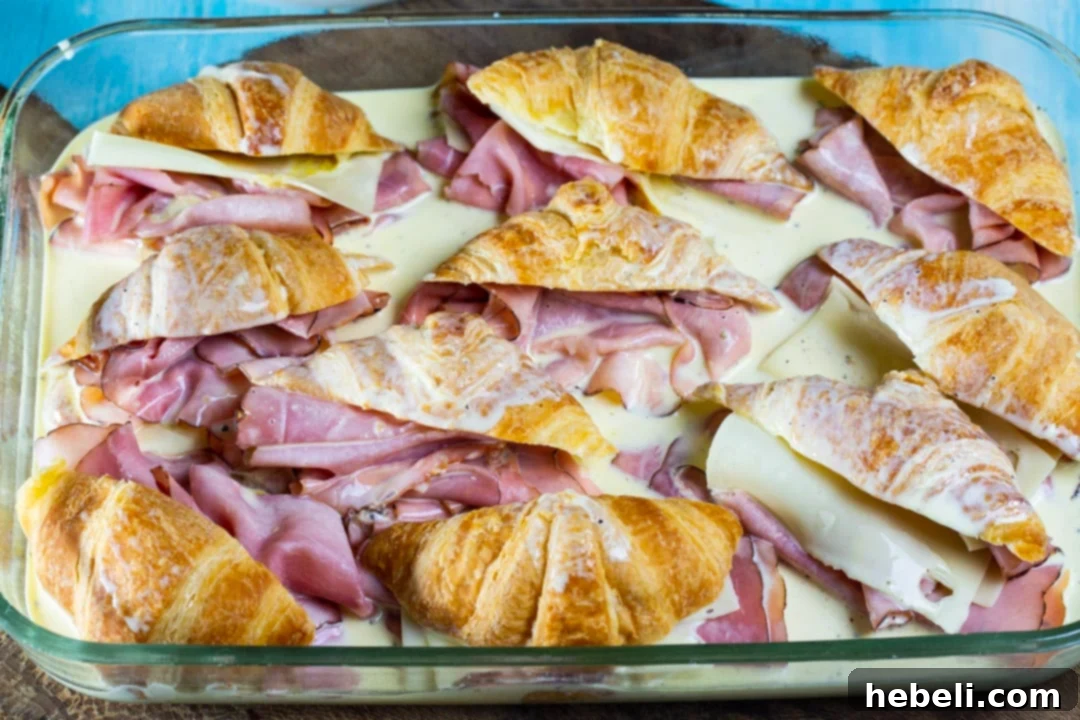 Savory Ham and Cheese Croissant Bake 5 The unbaked casserole, with ham and cheese stuffed croissants soaking in the rich egg and cream mixture, topped with cheese and green onions, ready for refrigeration.