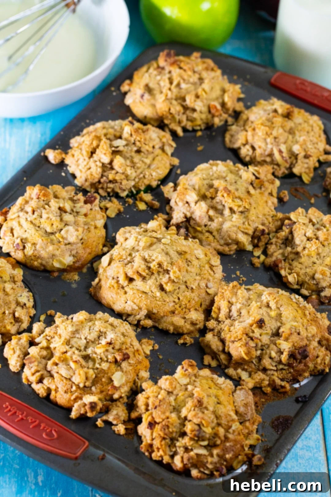 Freshly baked Apple Spice Muffins cooling in a muffin tin, showcasing their golden streusel topping.