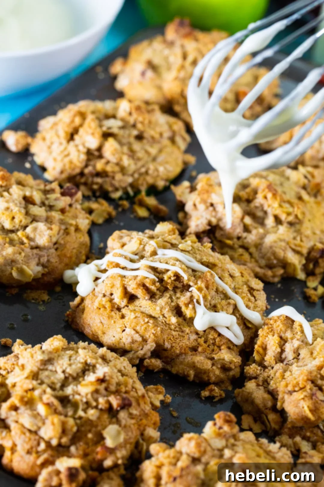 Close-up of a hand drizzling sweet glaze over warm Apple Spice Muffins.