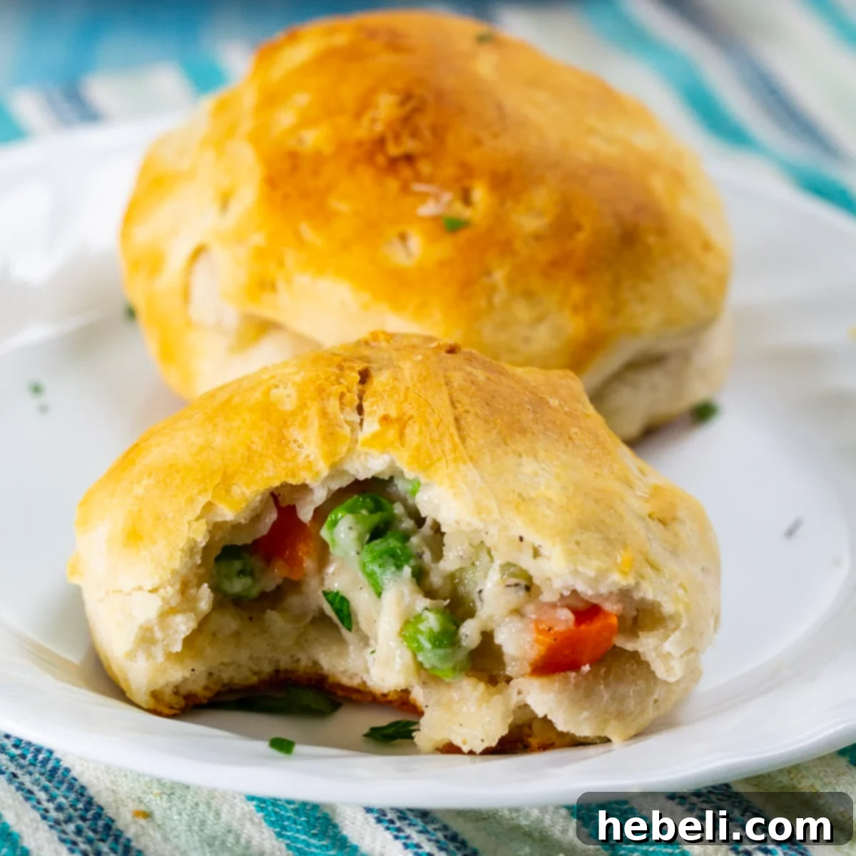 Hearty Chicken and Biscuit Pot Pie 2 Golden brown Chicken Pot Pie Biscuits with a bite taken out, revealing the creamy chicken and vegetable filling inside.