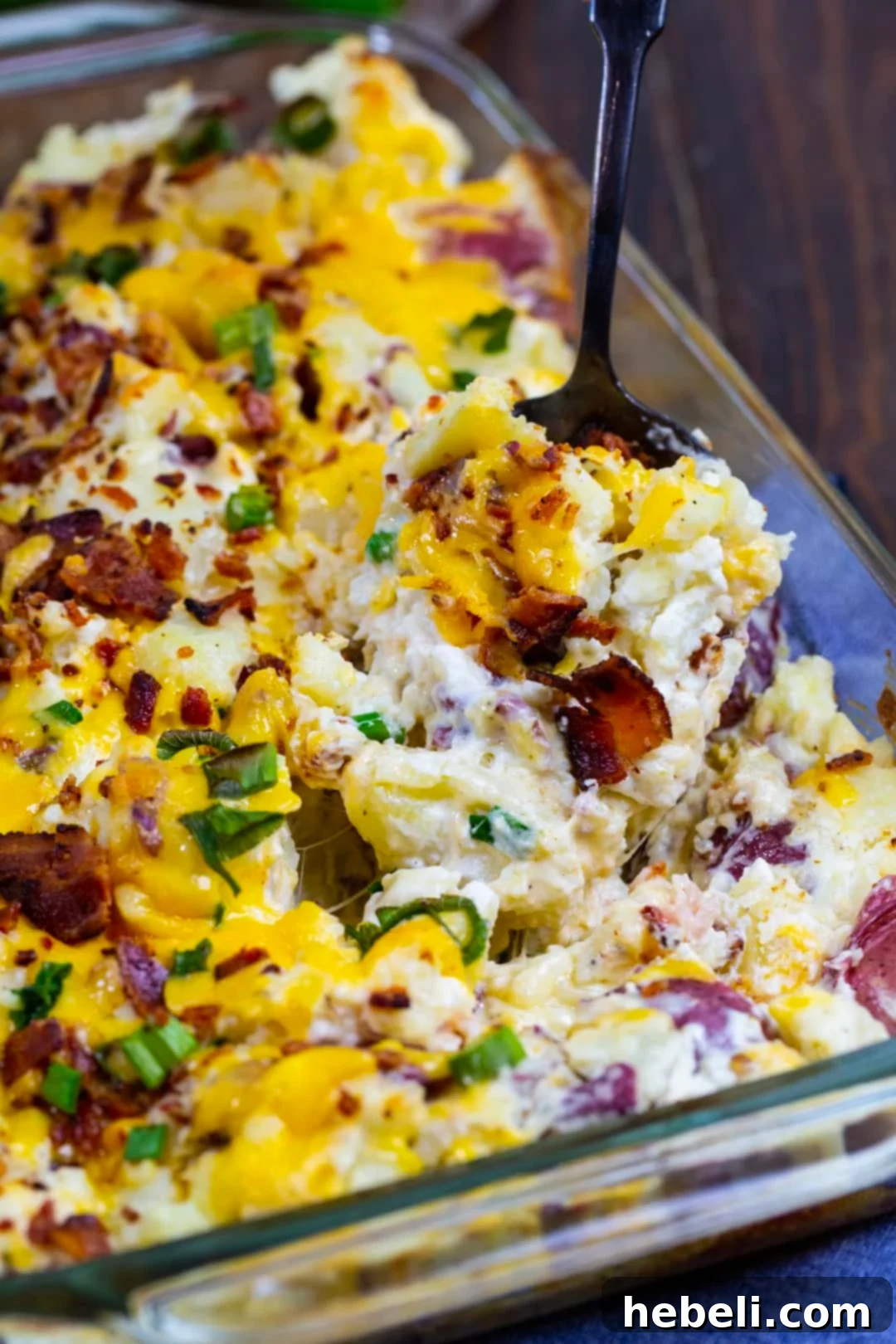 A spoon scooping up a generous, creamy portion of Loaded Smashed Potato Casserole, showcasing its rich texture and cheesy layers.