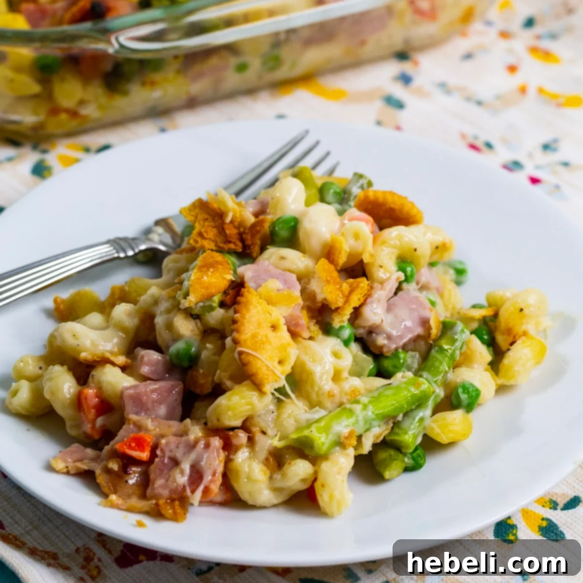 Savory Ham and Asparagus Bake 2 A generous serving of Ham and Asparagus Casserole dished up on a white plate, showcasing its creamy texture and golden topping.