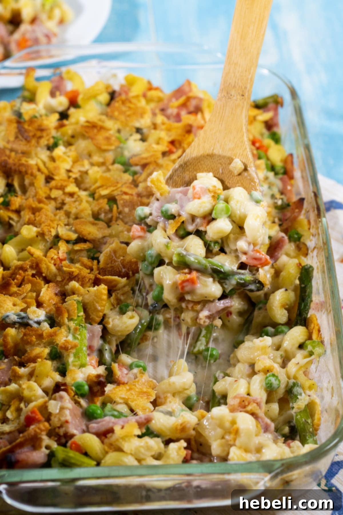 Savory Ham and Asparagus Bake 4 A serving spoon lifting a spoonful of the creamy Ham and Asparagus Casserole, showing off the pasta, ham, and asparagus.