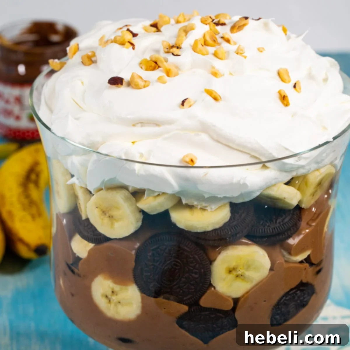 Decadent Nutella Banana Pudding 2 Nutella Banana Pudding in a trifle dish, showcasing layers of pudding, banana slices, and crushed Oreos.