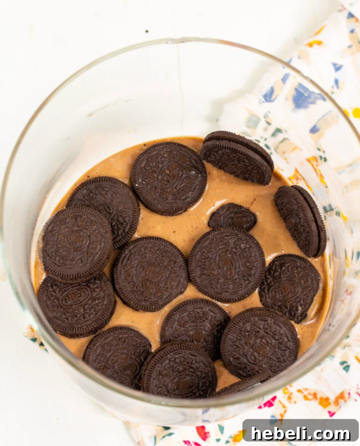 Decadent Nutella Banana Pudding 3 Oreo cookies meticulously placed on top of a smooth pudding layer in a clear trifle bowl, ready for the next layer of bananas.