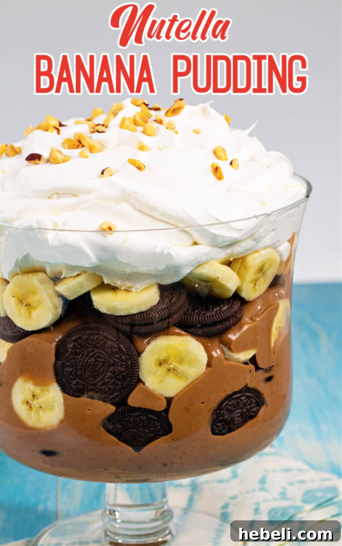 Decadent Nutella Banana Pudding 6 Close-up of Nutella Banana Pudding topped with a generous swirl of whipped cream and a sprinkle of chopped roasted hazelnuts, ready to be enjoyed.