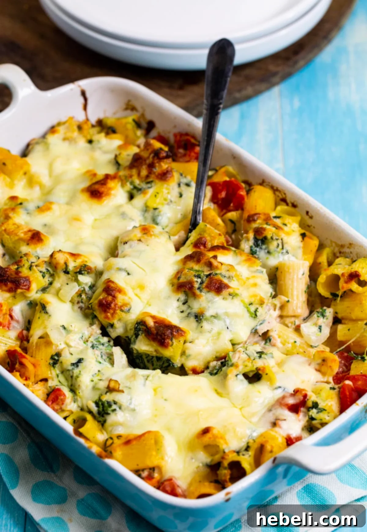 A full baking dish of Chicken Spinach Rigatoni, with a golden-brown cheese topping, ready to be served.