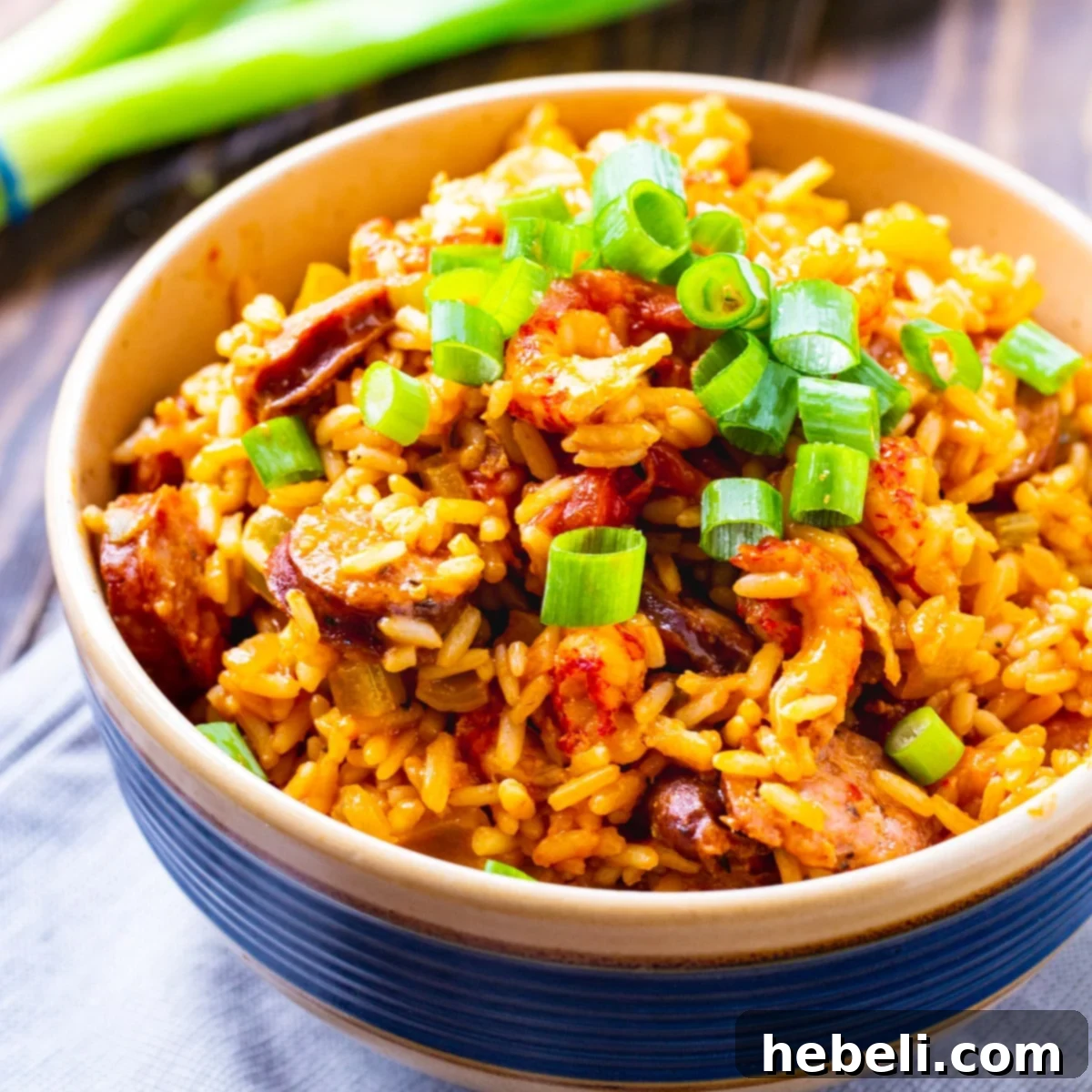 A generous bowl of homemade Crawfish Jambalaya, rich with rice, crawfish, and sausage, garnished with fresh green onions.