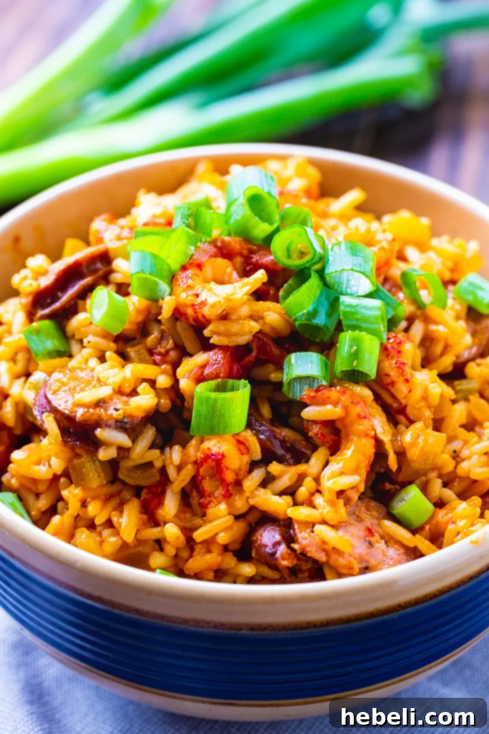 A beautifully presented bowl of Crawfish Jambalaya, garnished with fresh green onions, showcasing its rich texture and vibrant colors.