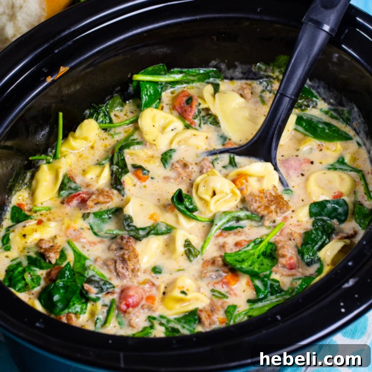 A large pot of Slow Cooker Creamy Tortellini and Sausage Soup, showcasing the creamy broth, tortellini, sausage, and spinach, ready to be served.