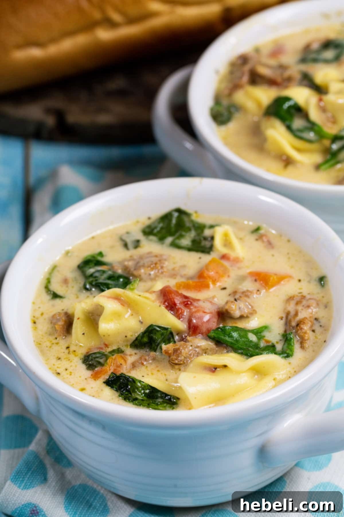 An inviting bowl of Slow Cooker Creamy Tortellini and Sausage Soup garnished with fresh herbs, ready to be enjoyed.
