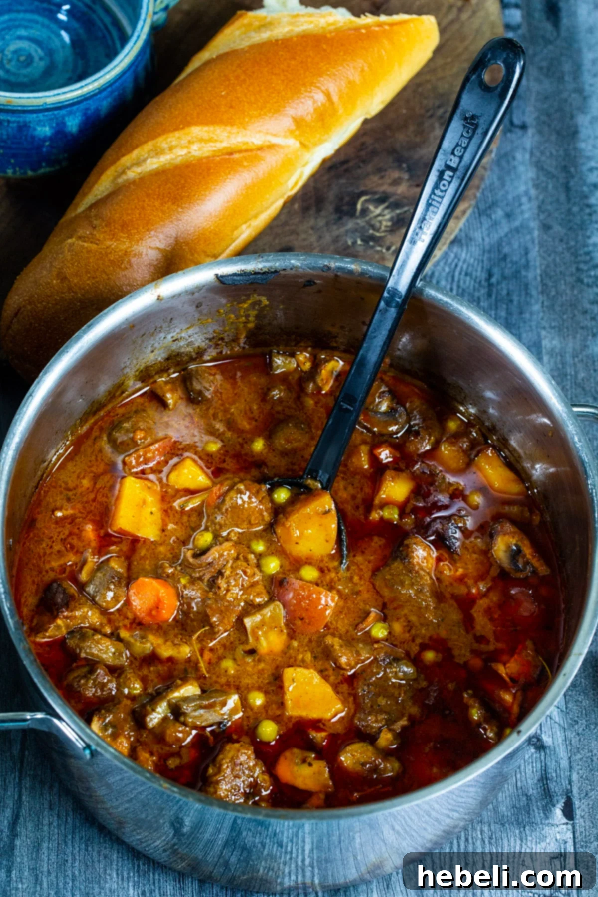Whiskey-Kissed Beef Stew 3 A large Dutch oven filled with Bourbon Beef Stew, accompanied by a loaf of crusty French bread, ready to be served.