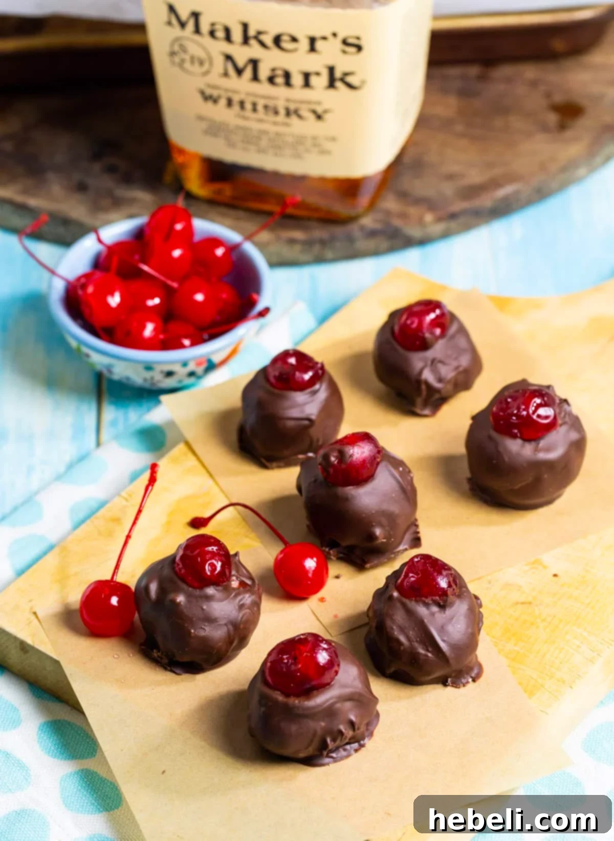 Ingredients for Cherry Bourbon Balls: a bowl of finished bourbon balls, fresh maraschino cherries, and a bottle of fine bourbon.