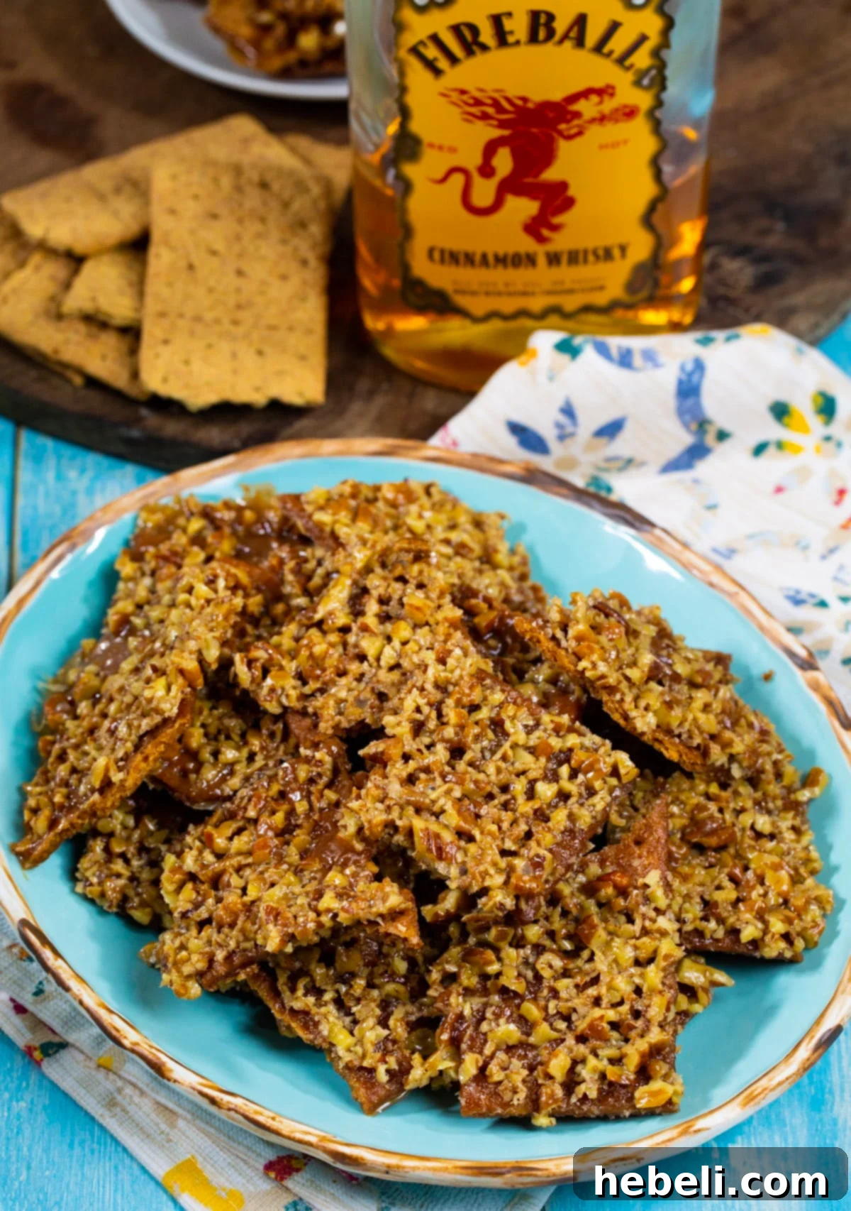 Graham Cracker Candy on a plate with a bottle of Fireball Cinnamon Whisky in the background.