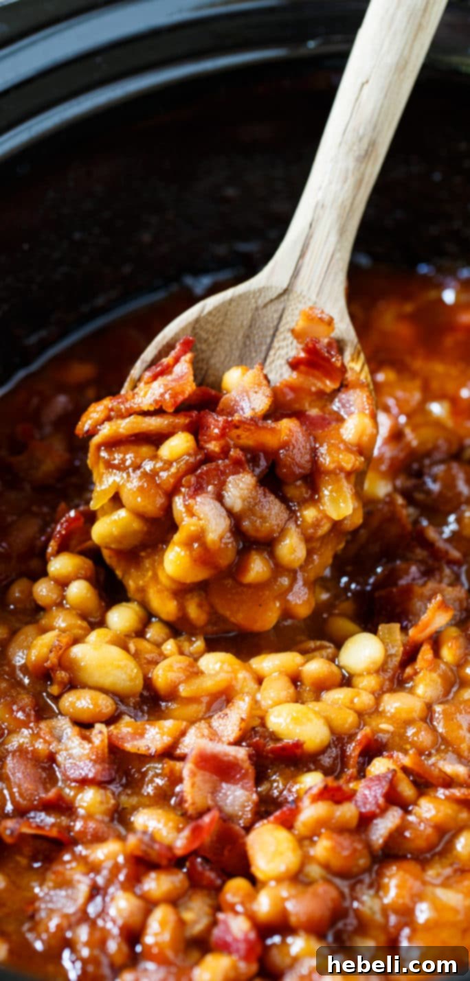 A spoonful of Slow Cooker Bourbon Baked Beans, highlighting the rich sauce, beans, and bacon bits.