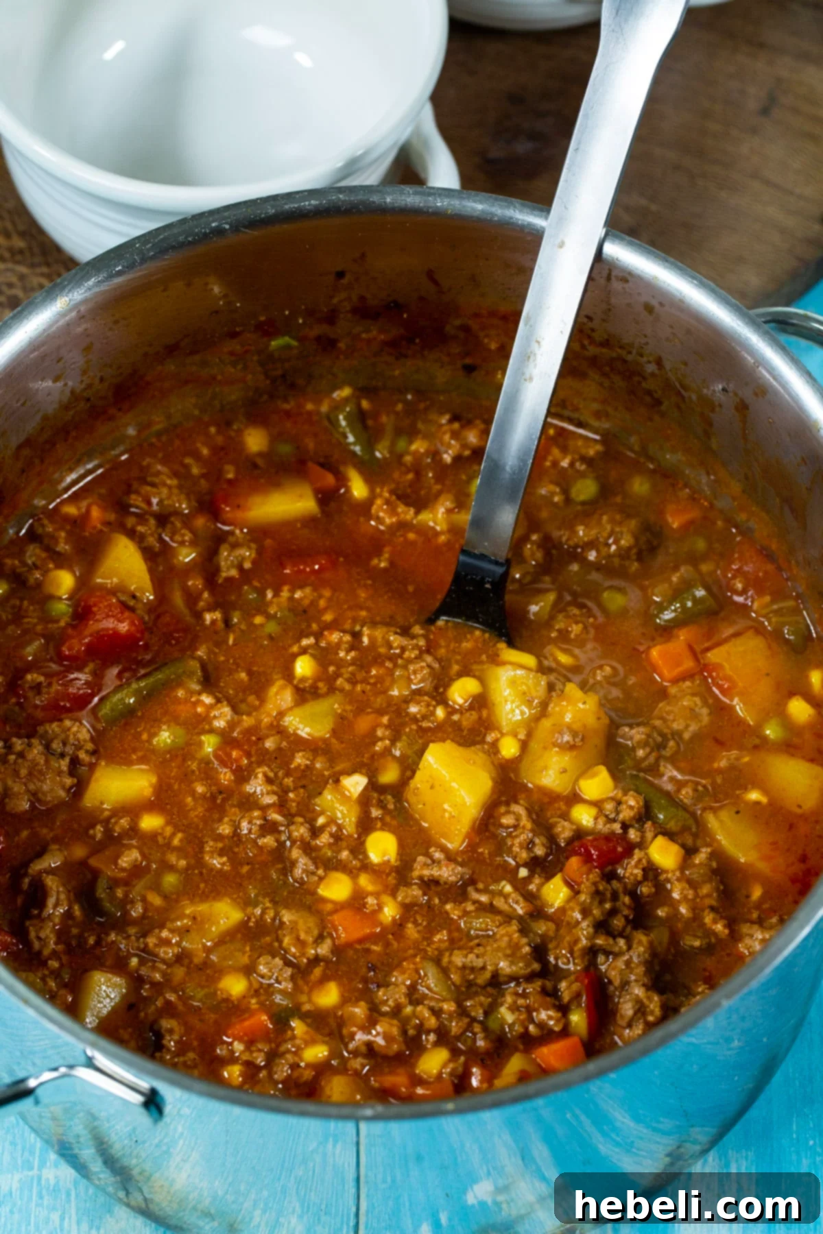 Hearty Hamburger Stew simmering in a Dutch oven, rich with vegetables and beef.