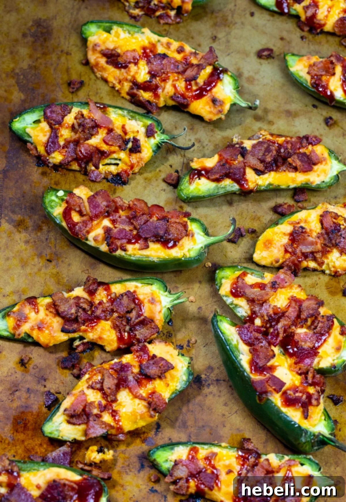 Perfectly stuffed and golden-brown jalapenos baking on a sheet pan, showing the rich filling.
