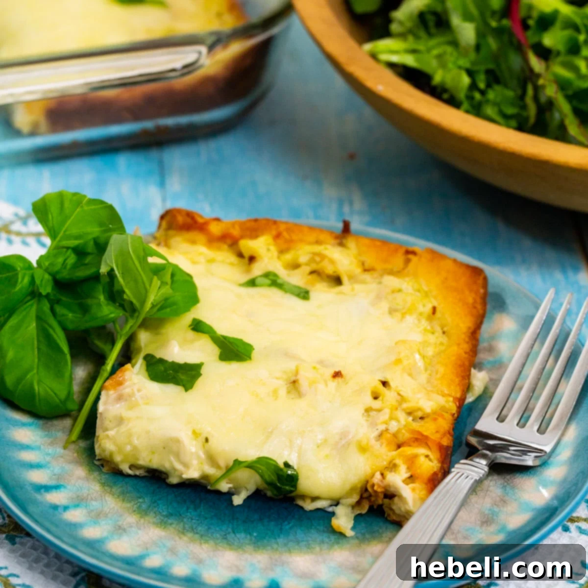 Cheesy Chicken Alfredo Crescent Rolls 2 Square of Chicken Alfredo Crescent Bake on a white plate, showcasing its golden crust and creamy filling.