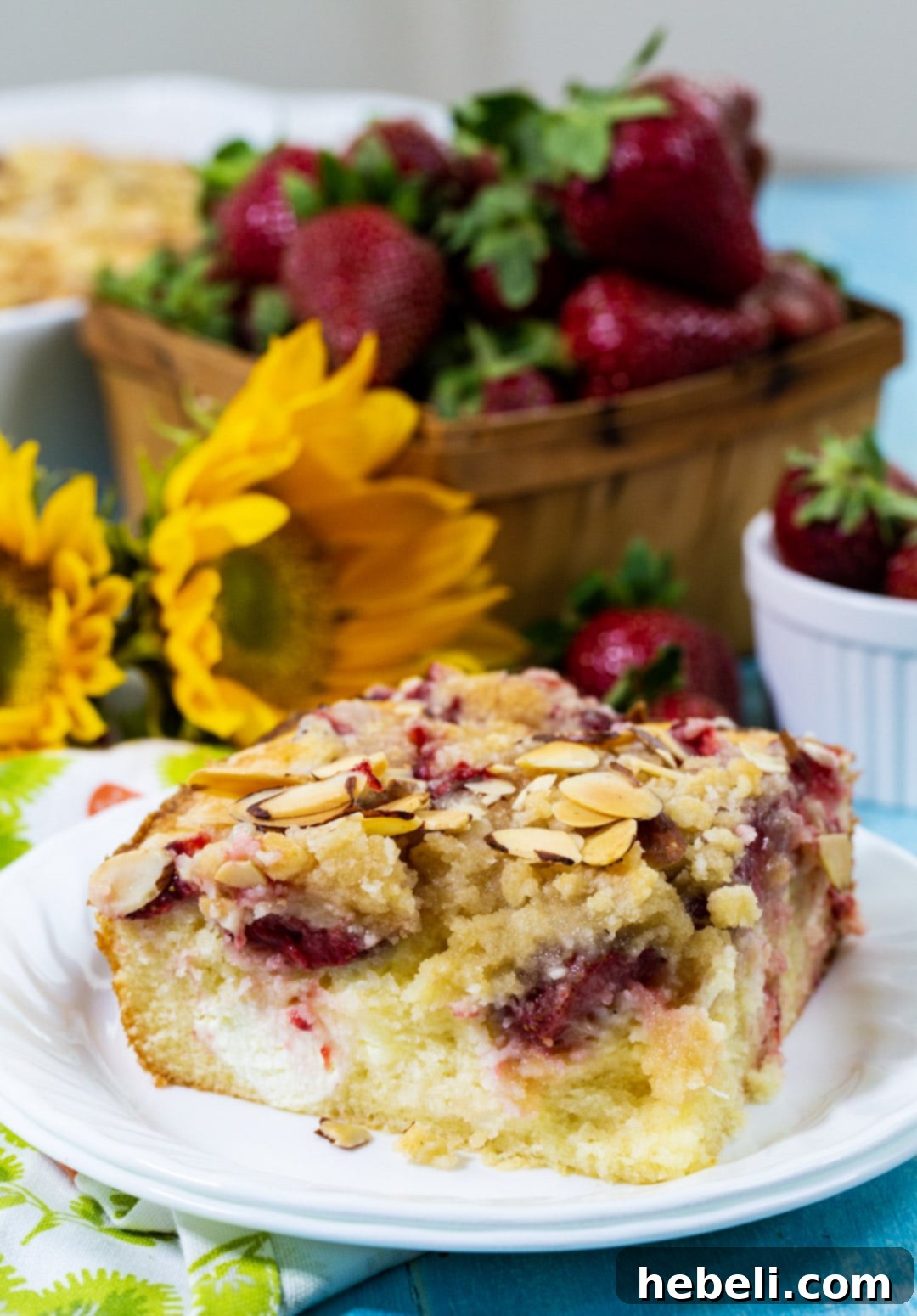 A close-up view of a serving of Strawberry Cream Cheese Coffee Cake, highlighting the textures of the crumb topping, baked strawberries, and soft cake.
