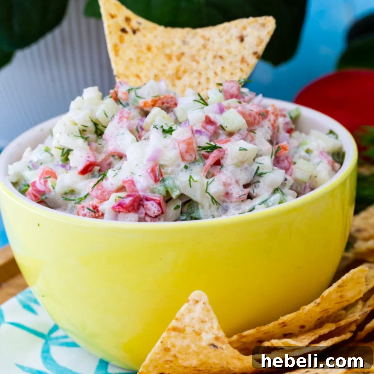 A tortilla chip being dipped into a bowl of refreshing Creamy Cucumber Salsa, showcasing its vibrant ingredients.