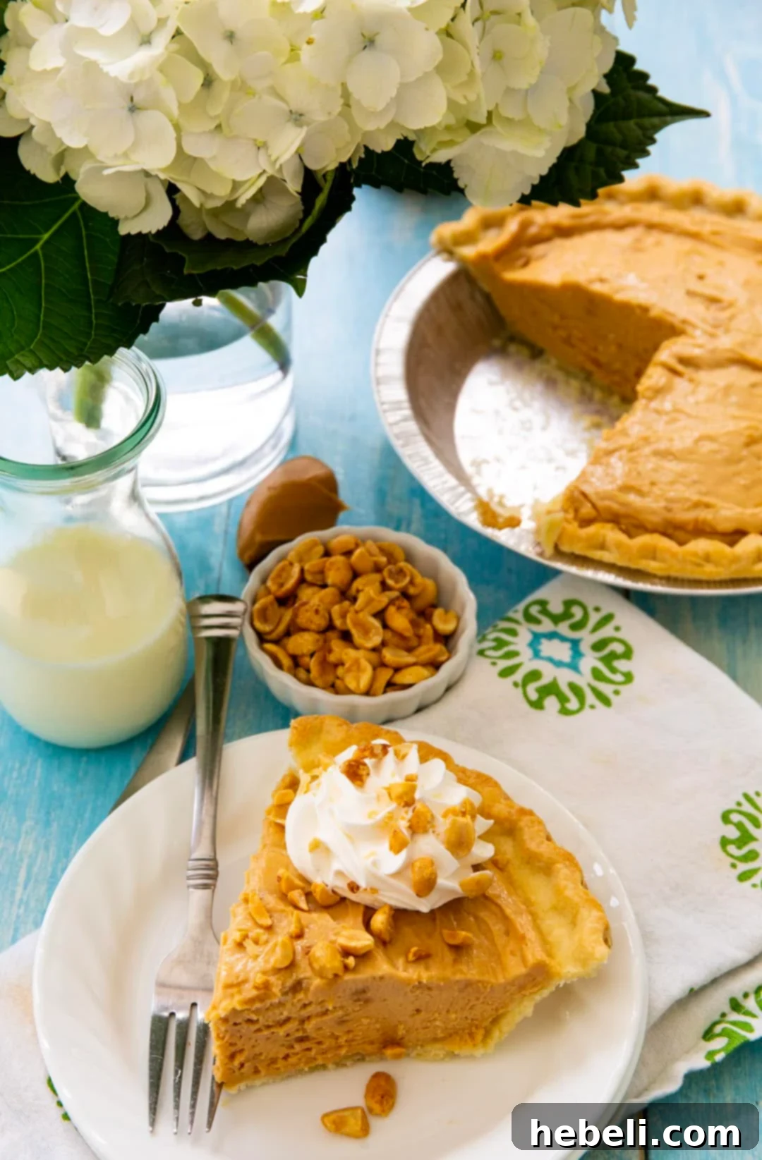 Homestyle Peanut Butter Pie 5 A slice of creamy Old-Fashioned Peanut Butter Pie next to a small bowl of crunchy roasted peanuts, highlighting the potential for delicious garnishes.