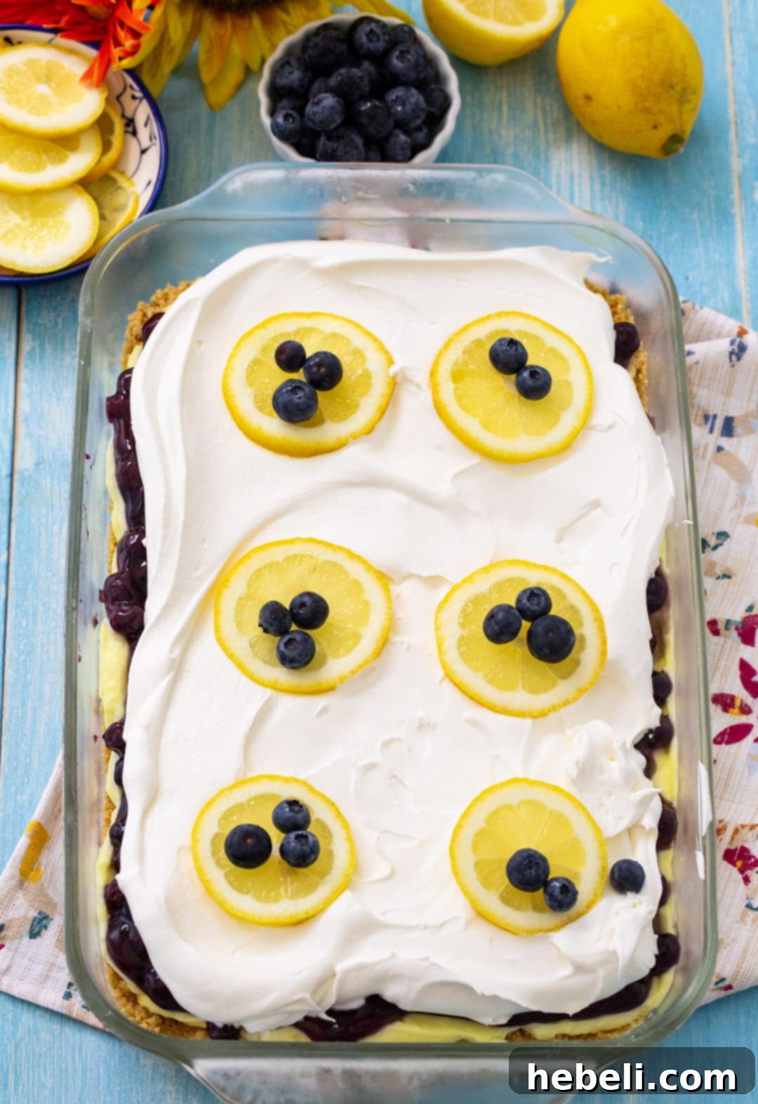 Close-up of the Blueberry Lemon Layer Dessert in a baking dish, highlighting its creamy texture and vibrant fruit layer, with a slight dip showing where a slice has been removed, ready to be served.
