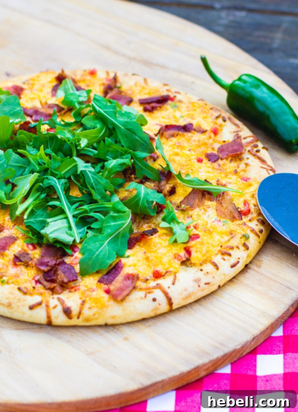 A delicious whole Pimento Cheese Pizza, freshly baked to a golden crust and placed on a pizza peel, ready to be sliced and served.
