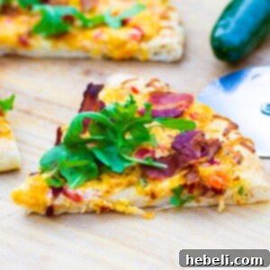 A perfectly baked slice of Pimento Cheese Pizza topped with fresh arugula, ready to be served.