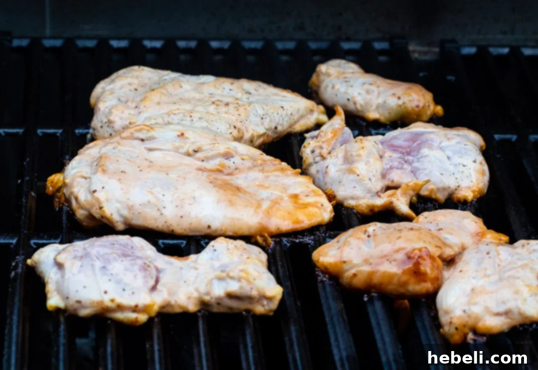 Smoky Tangy Grilled Chicken 4 Chicken sizzling on a hot grill, showing distinct grill marks and a golden-brown hue.