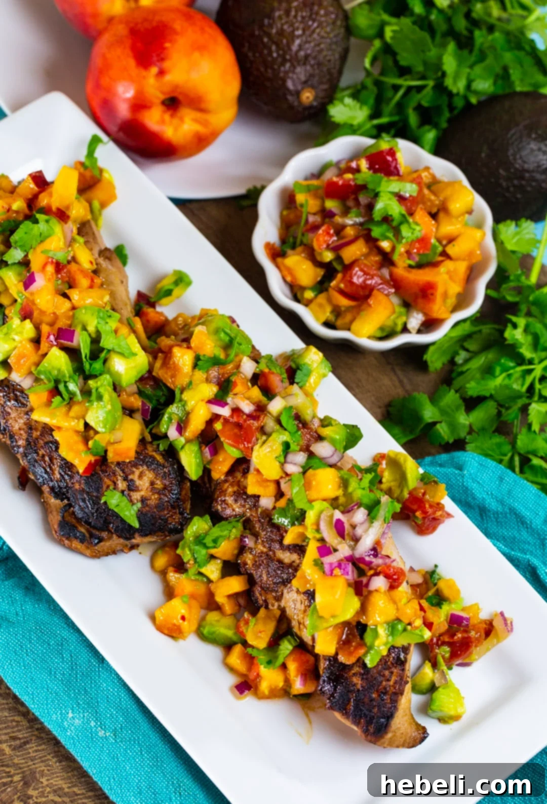 Seared Pork Tenderloin with Bright Nectarine Avocado Salsa 3 Close-up of cooked pork tenderloin covered in a vibrant nectarine avocado salsa, alongside a fresh bowl of the colorful salsa ingredients.