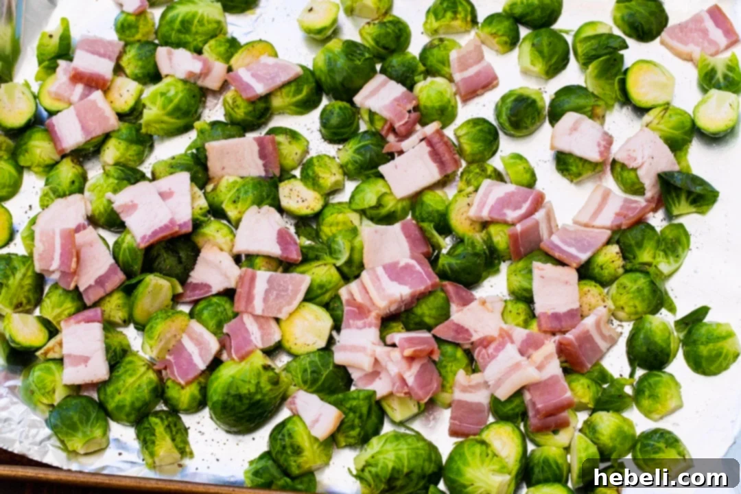Uncooked Brussels sprouts and bacon pieces arranged on a baking sheet before roasting.