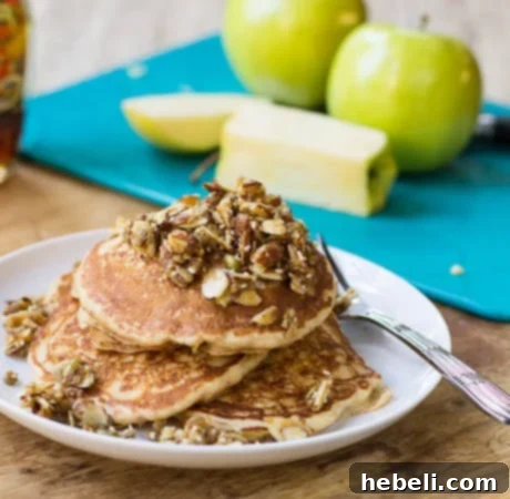 Apple Pancakes with Nutty Topping on a plate with Golden Delicious apples in background.