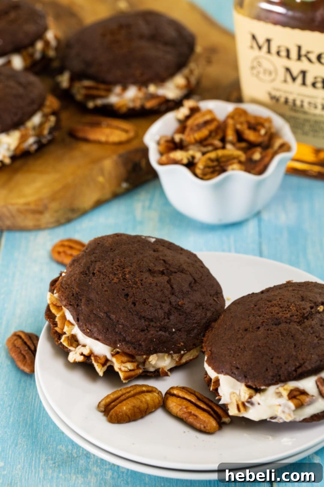 A charming still life featuring Whiskey Whoopie Pies accompanied by a bowl of whole pecans, emphasizing the dessert's rustic elegance.