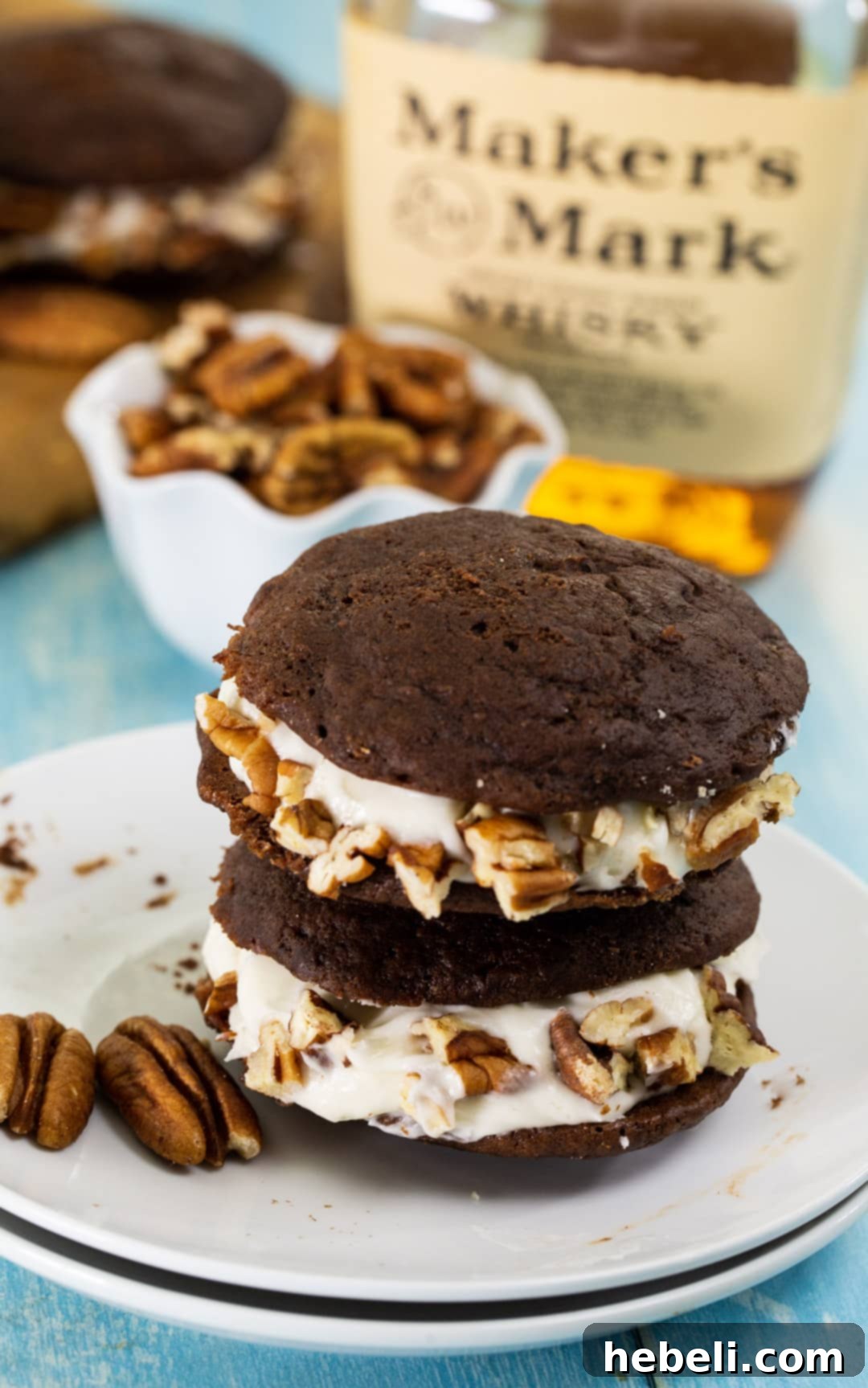 Two perfectly assembled cream-filled cookies, representing the Whiskey Whoopie Pies, stacked on a clean surface, highlighting the creamy filling.