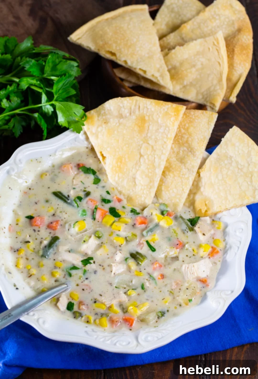 Hearty Chicken Pot Pie Soup 5 A hearty bowl of Chicken Pot Pie Soup generously garnished with several perfectly golden pie crust pieces and fresh parsley, ready to be enjoyed.
