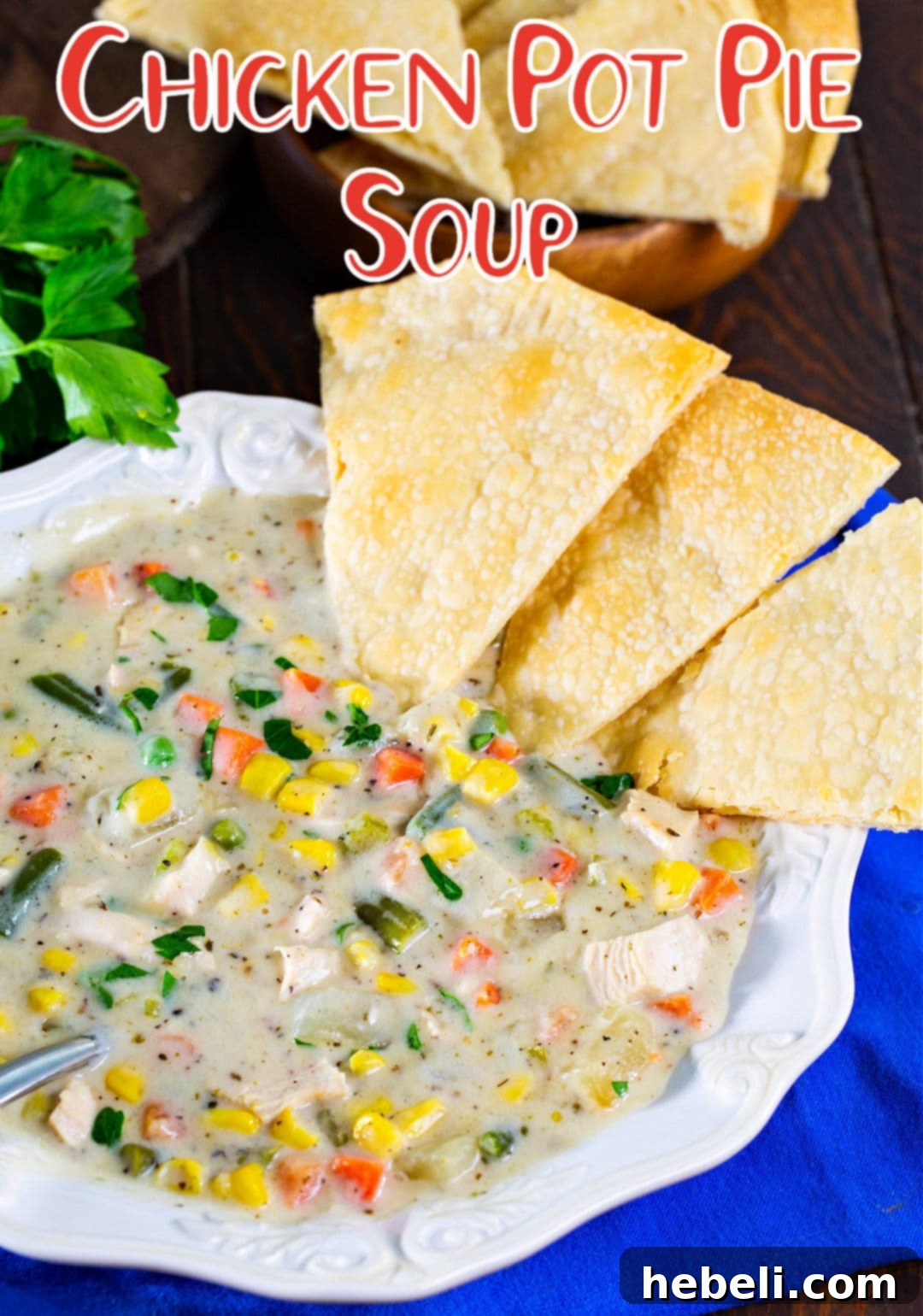 Hearty Chicken Pot Pie Soup 6 A beautifully presented bowl of creamy Chicken Pot Pie Soup, garnished with fresh green herbs and several crispy pie crust pieces on the side.