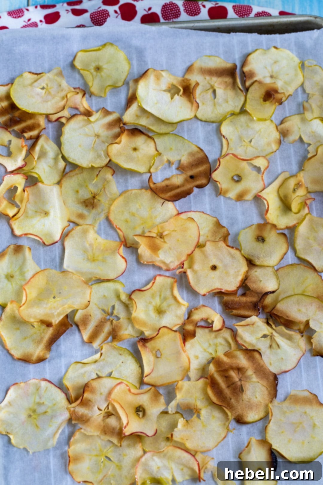 Caramelized Apple Chips cooling on parchment paper-lined baking sheet.