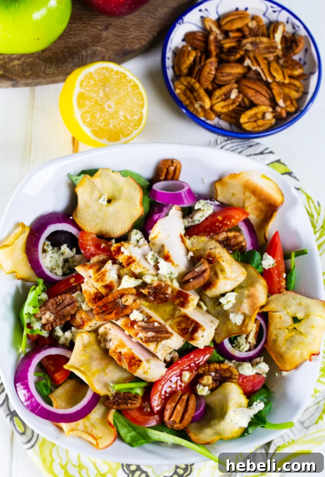 Fuji Mountain Chicken Medley 3 A beautifully presented Fuji Apple Chicken Salad in a bowl, with a separate bowl of toasted pecans, emphasizing the nutty crunch.