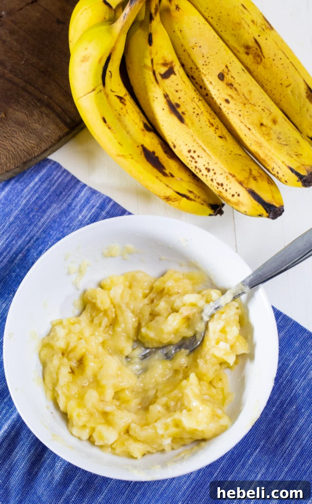 Close-up shot of perfectly mashed ripe bananas in a glass bowl, ready to be incorporated into the cake batter.