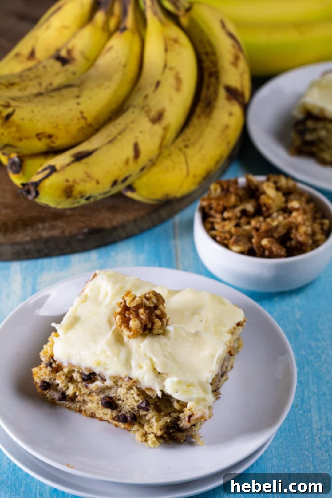 A generous slice of Banana Cake with Cream Cheese Frosting and candied walnuts on a rustic plate, highlighting its moist texture and rich layers.