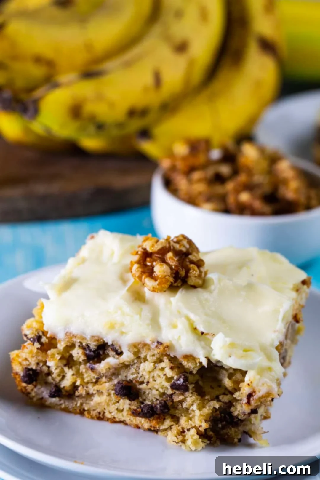 A perfectly portioned slice of Banana Cake with Cream Cheese Frosting, beautifully garnished with candied walnuts, resting on a white plate.